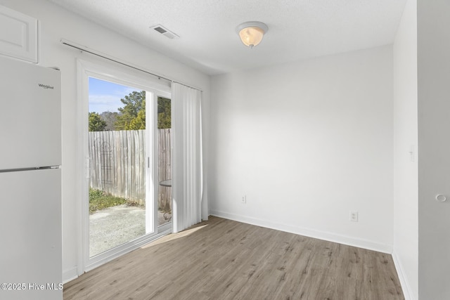 empty room with a textured ceiling and light wood-type flooring