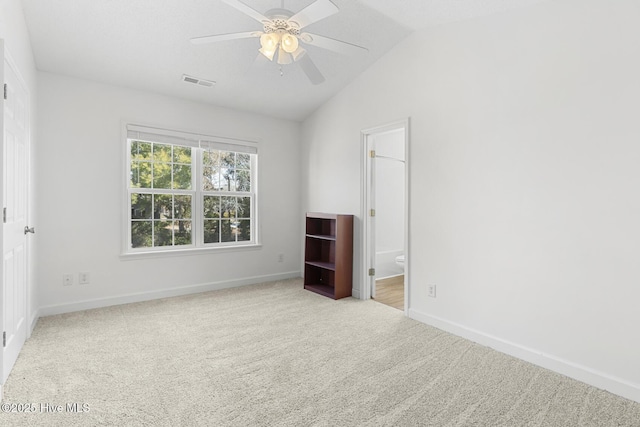 unfurnished bedroom with ceiling fan, connected bathroom, vaulted ceiling, and light carpet