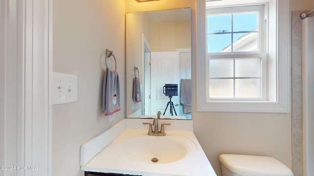 bathroom with vanity, toilet, and a healthy amount of sunlight