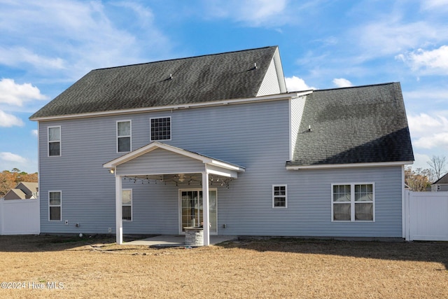 back of property with a patio area, fence, roof with shingles, and a lawn