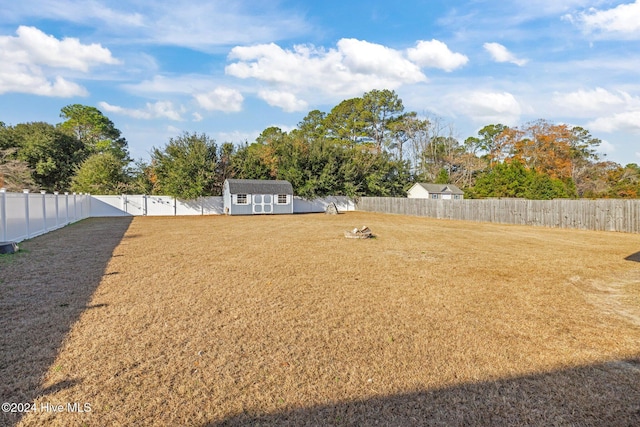 view of yard with a storage unit, an outdoor structure, a fenced backyard, and a gate