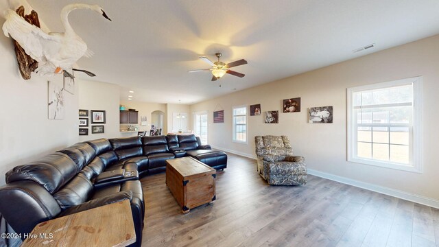 living room featuring ceiling fan, visible vents, baseboards, and wood finished floors