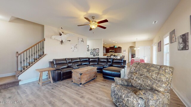 living area featuring visible vents, baseboards, a ceiling fan, and wood finished floors