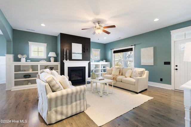 living room with ceiling fan, a large fireplace, and hardwood / wood-style flooring