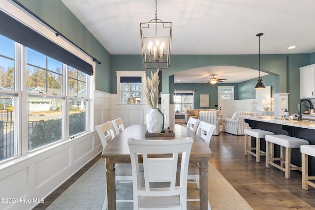 dining space featuring dark hardwood / wood-style flooring, ceiling fan with notable chandelier, and sink