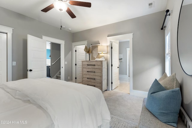 bedroom featuring ensuite bath, ceiling fan, and light carpet