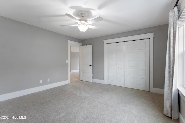 unfurnished bedroom with ceiling fan, light carpet, and a closet