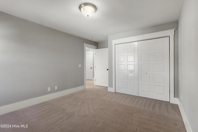 unfurnished bedroom featuring light carpet and a closet