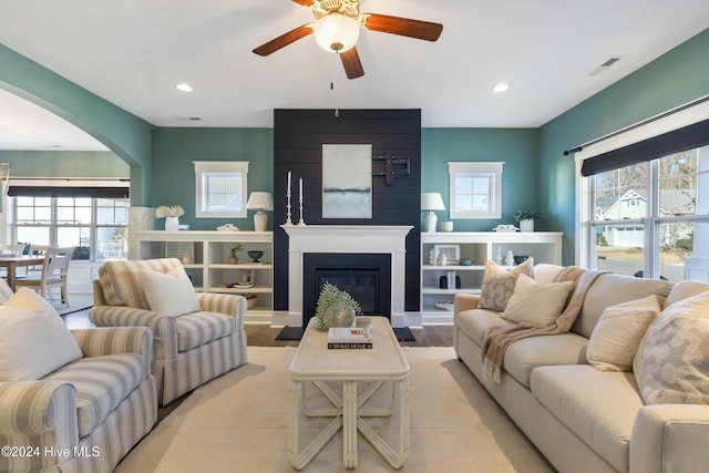 living room featuring ceiling fan and a fireplace