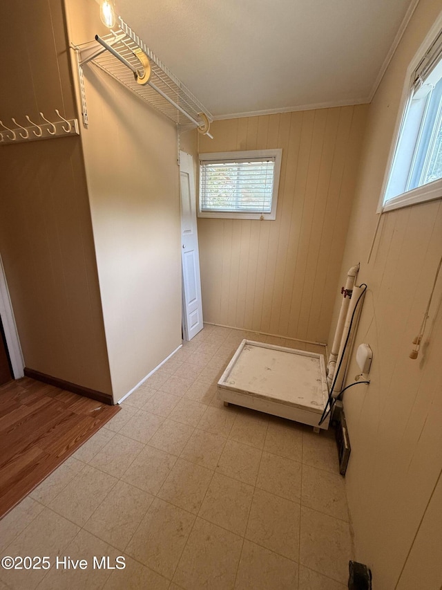 clothes washing area with tile patterned floors, wooden walls, a healthy amount of sunlight, and crown molding