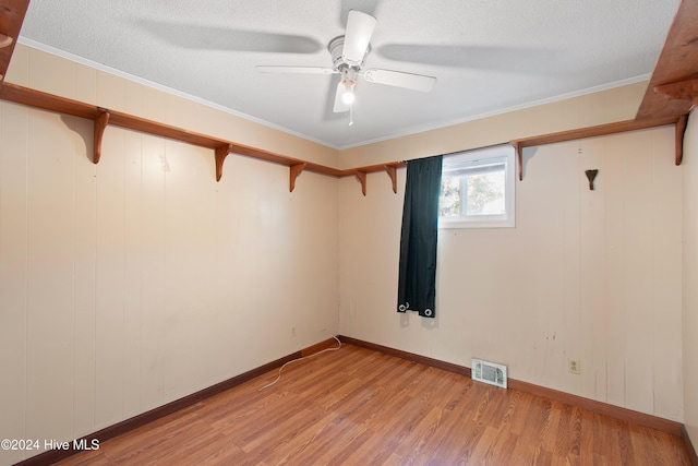 empty room with visible vents, light wood-style floors, ornamental molding, and a ceiling fan