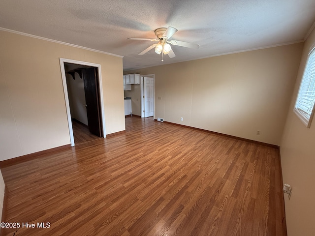 empty room with ornamental molding, ceiling fan, and wood finished floors