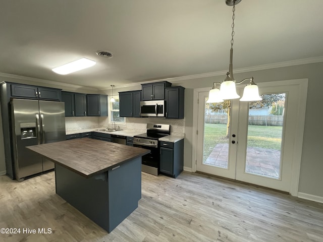 kitchen featuring plenty of natural light, a kitchen island, decorative light fixtures, and appliances with stainless steel finishes