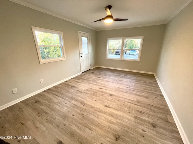 spare room with light hardwood / wood-style floors, a wealth of natural light, and ornamental molding