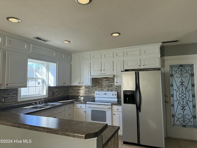 kitchen featuring kitchen peninsula, stainless steel fridge, white electric range oven, sink, and white cabinetry