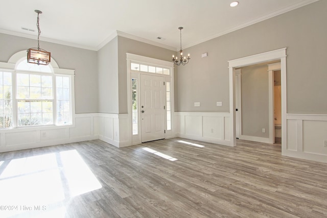 foyer with a notable chandelier, wood-type flooring, and ornamental molding