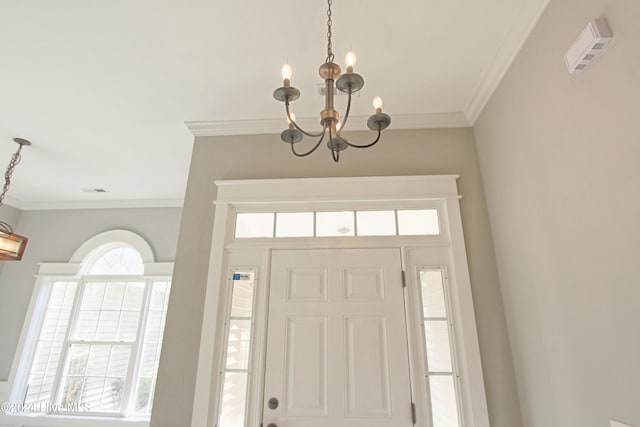 entrance foyer with ornamental molding and a chandelier