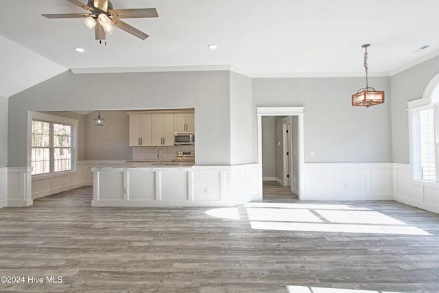 unfurnished living room featuring crown molding, light hardwood / wood-style flooring, ceiling fan, and sink