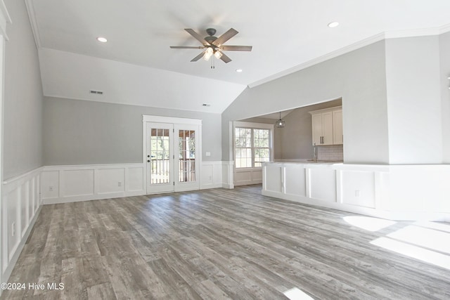 unfurnished living room featuring ceiling fan, wood-type flooring, vaulted ceiling, and ornamental molding