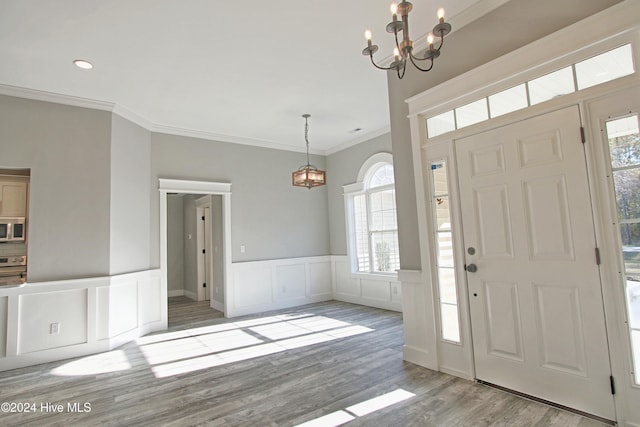 entryway featuring light hardwood / wood-style floors, crown molding, a healthy amount of sunlight, and an inviting chandelier