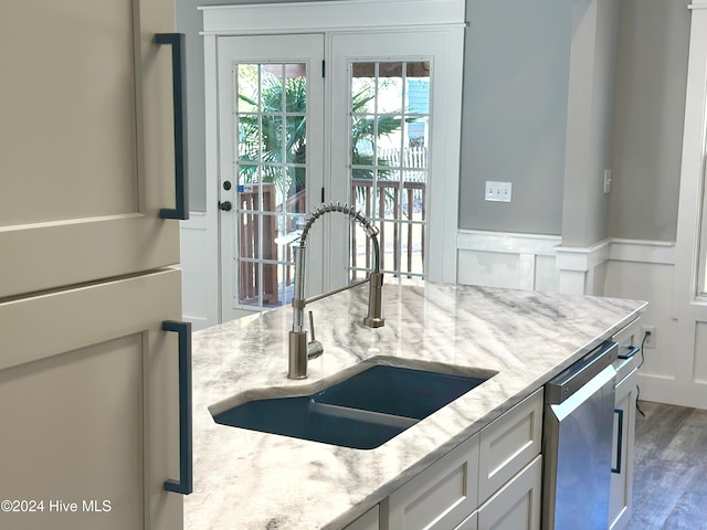 kitchen featuring light stone counters, stainless steel dishwasher, sink, dark hardwood / wood-style floors, and white cabinetry