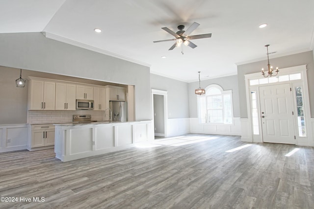 kitchen with light wood-type flooring, ornamental molding, stainless steel appliances, a center island, and hanging light fixtures