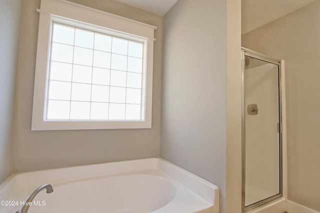 bathroom featuring a healthy amount of sunlight and separate shower and tub