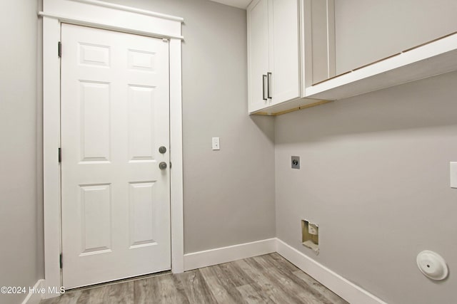 laundry room featuring hookup for an electric dryer, light hardwood / wood-style floors, and cabinets