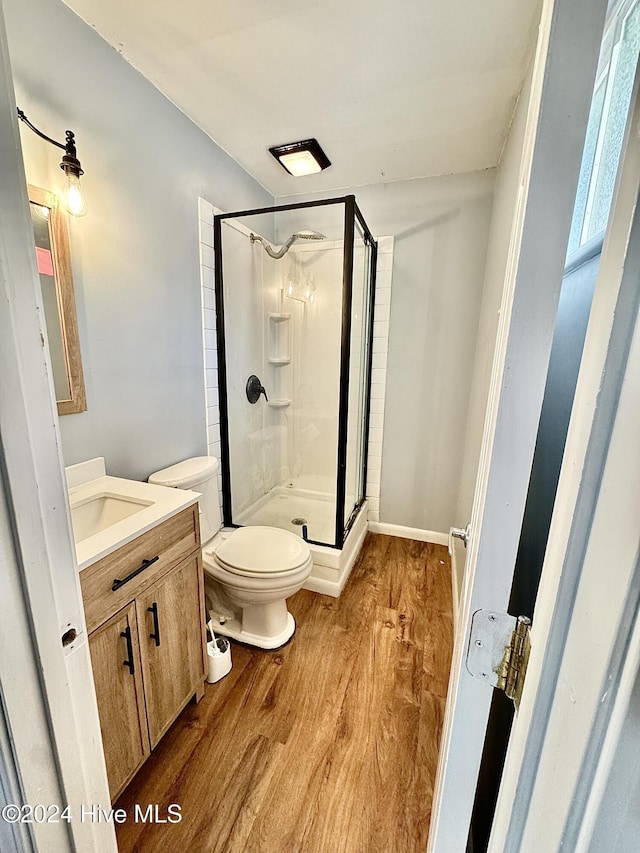 bathroom featuring hardwood / wood-style floors, vanity, toilet, and a shower with shower door