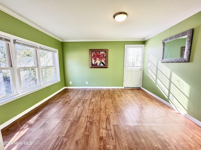 spare room featuring ornamental molding, light wood-type flooring, and a healthy amount of sunlight