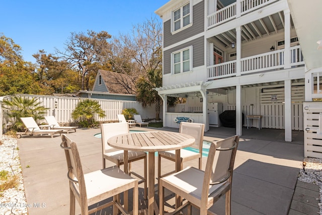 view of patio featuring fence, outdoor dining space, a balcony, and a fenced in pool