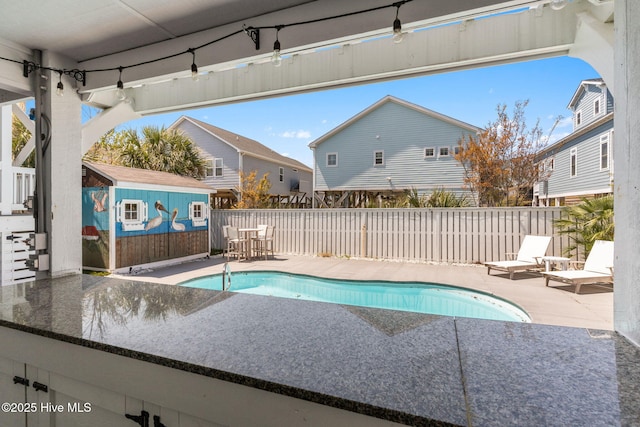 view of pool with a patio, an outbuilding, a fenced in pool, a shed, and fence