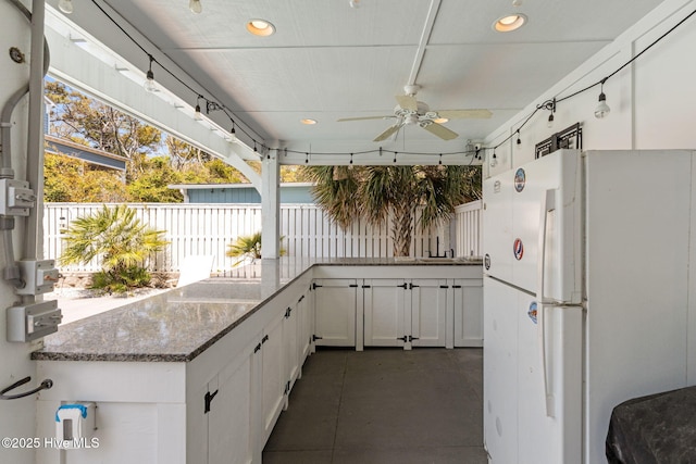 view of patio / terrace featuring fence, exterior kitchen, and a ceiling fan