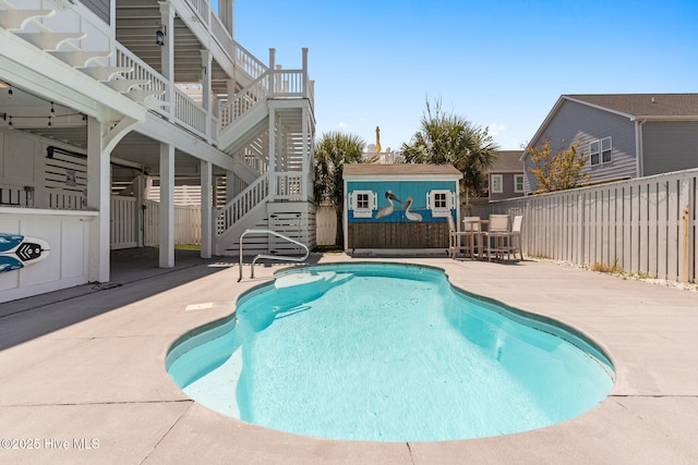 view of pool featuring a patio, a fenced in pool, an outbuilding, stairway, and a fenced backyard