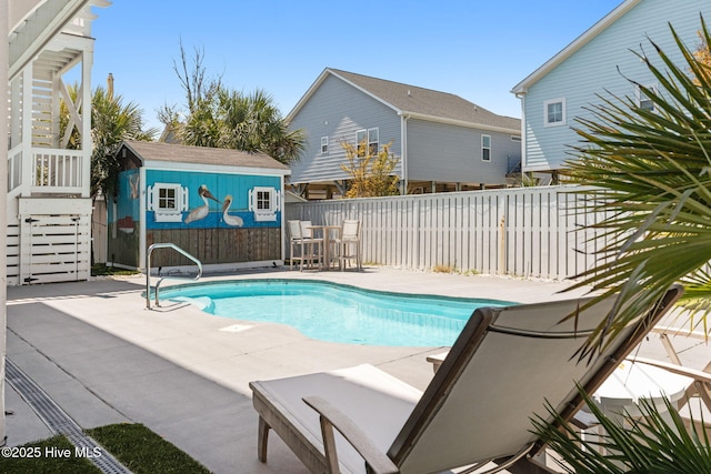 view of swimming pool featuring an outdoor structure, a fenced in pool, a storage unit, a patio area, and a fenced backyard