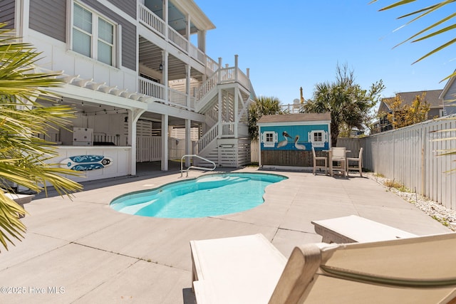 view of swimming pool featuring a fenced backyard, a storage unit, a fenced in pool, a patio, and stairs