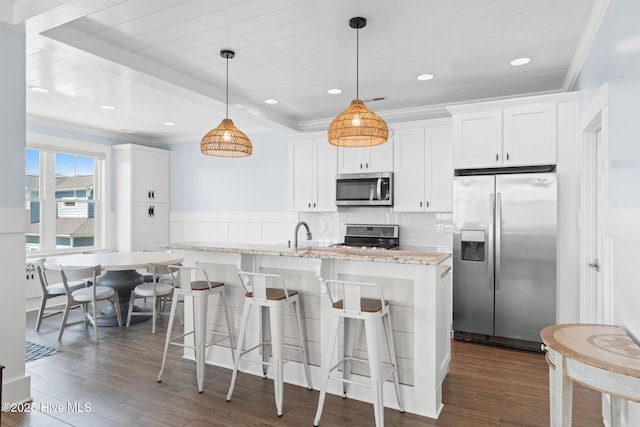 kitchen featuring appliances with stainless steel finishes, dark wood-type flooring, white cabinetry, and hanging light fixtures