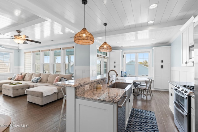 kitchen with hardwood / wood-style floors, wainscoting, appliances with stainless steel finishes, and a sink