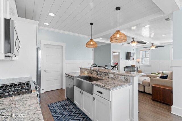 kitchen featuring white cabinetry, a wainscoted wall, appliances with stainless steel finishes, and a sink