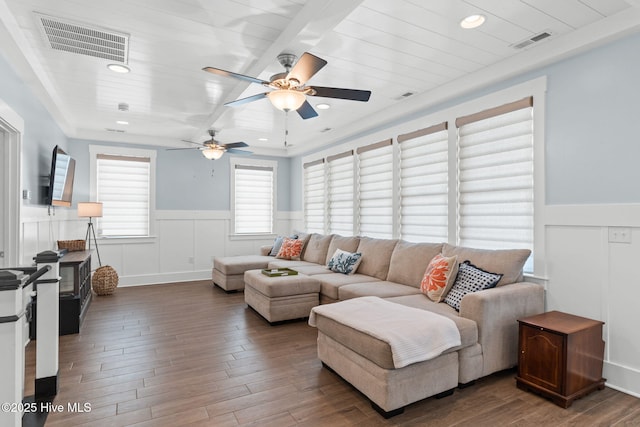living area with wood finished floors, visible vents, and a wainscoted wall