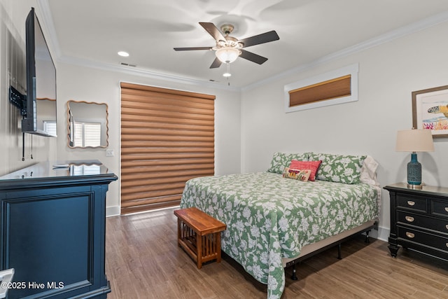 bedroom featuring crown molding, ceiling fan, wood finished floors, and visible vents