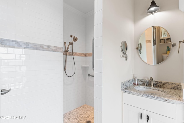 bathroom featuring crown molding, a tile shower, and vanity