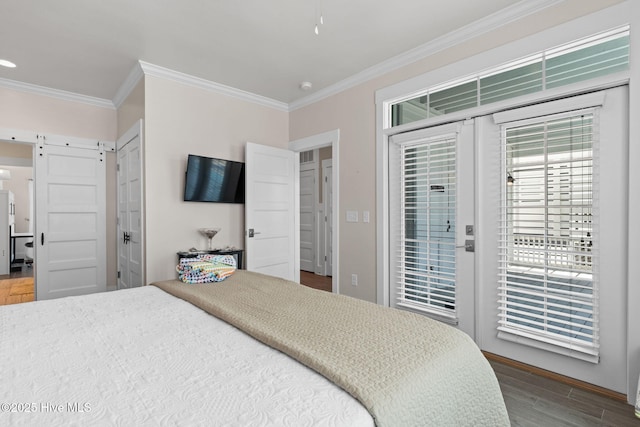 bedroom featuring a barn door, ornamental molding, access to outside, and wood finished floors