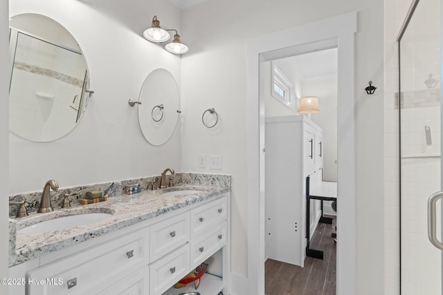 full bath featuring wood finished floors, crown molding, tiled shower, and a sink
