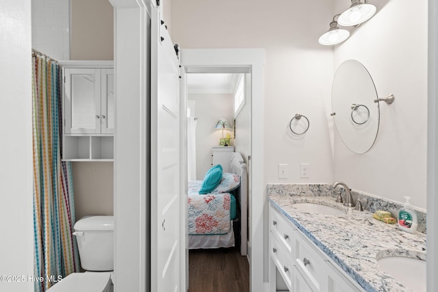 bathroom with wood finished floors, ensuite bath, double vanity, a sink, and crown molding