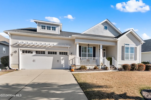 view of front of home with covered porch, a garage, and a front lawn