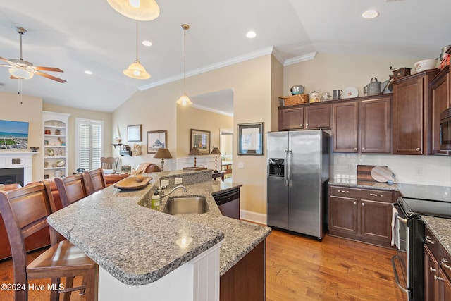 kitchen with a kitchen bar, appliances with stainless steel finishes, pendant lighting, and sink