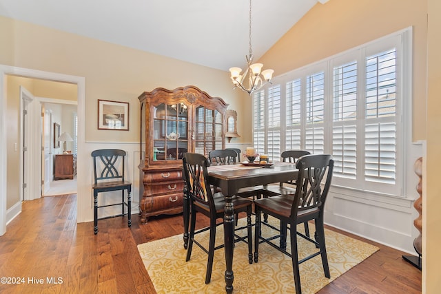 dining area featuring hardwood / wood-style floors, lofted ceiling, and a chandelier