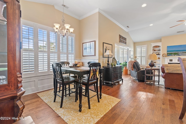 dining space with hardwood / wood-style flooring, built in shelves, a healthy amount of sunlight, and crown molding