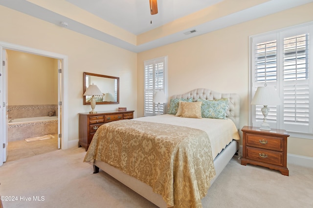 bedroom with multiple windows, ceiling fan, ensuite bathroom, and light carpet